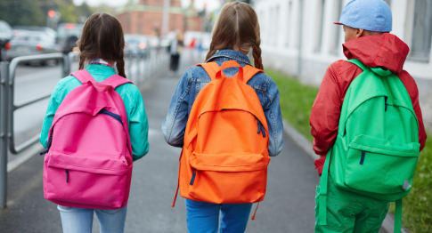 3 children with rucksacks going to school